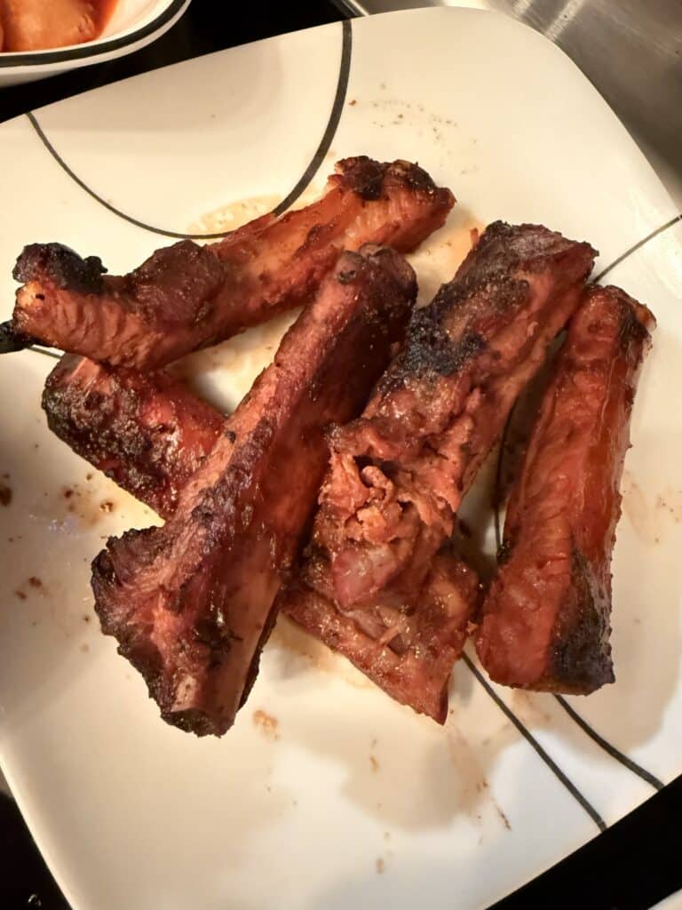 China Garden's grilled pork ribs with a dark, caramelized exterior arranged on a white plate.