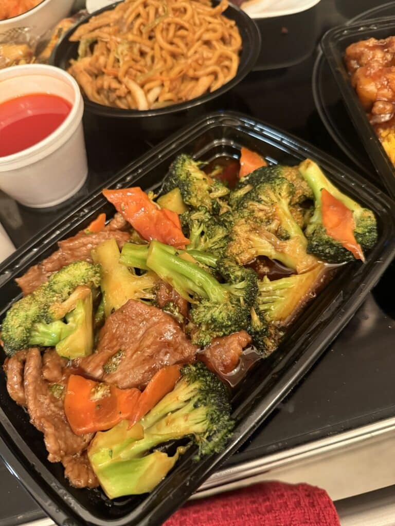 China Garden dinner in a black container with broccoli, chicken, and noodles.