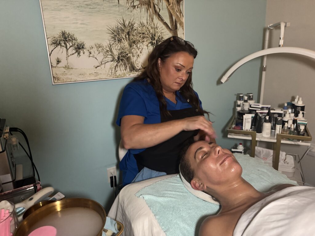Close-up of esthetician massaging serum into client’s face during facial treatment at Glowing Results Skin Spa.
