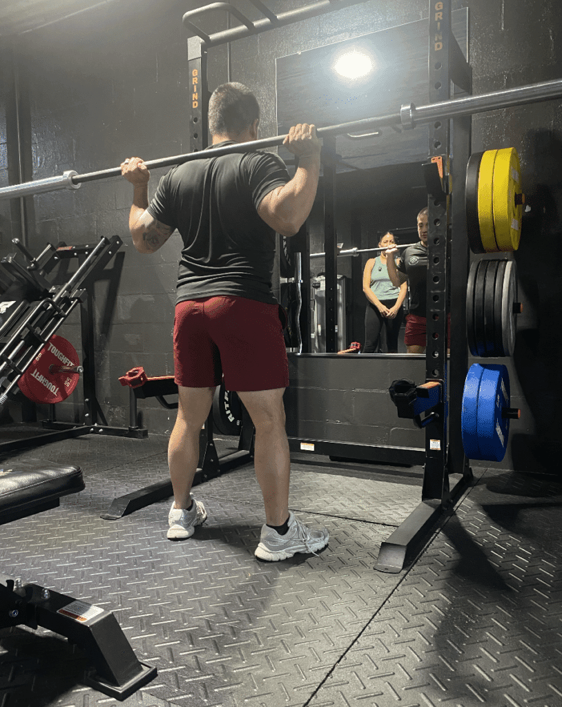 Personal Trainer showing client how to lift barbell at Prime Strength And Conditioning in Cape Coral, FL.