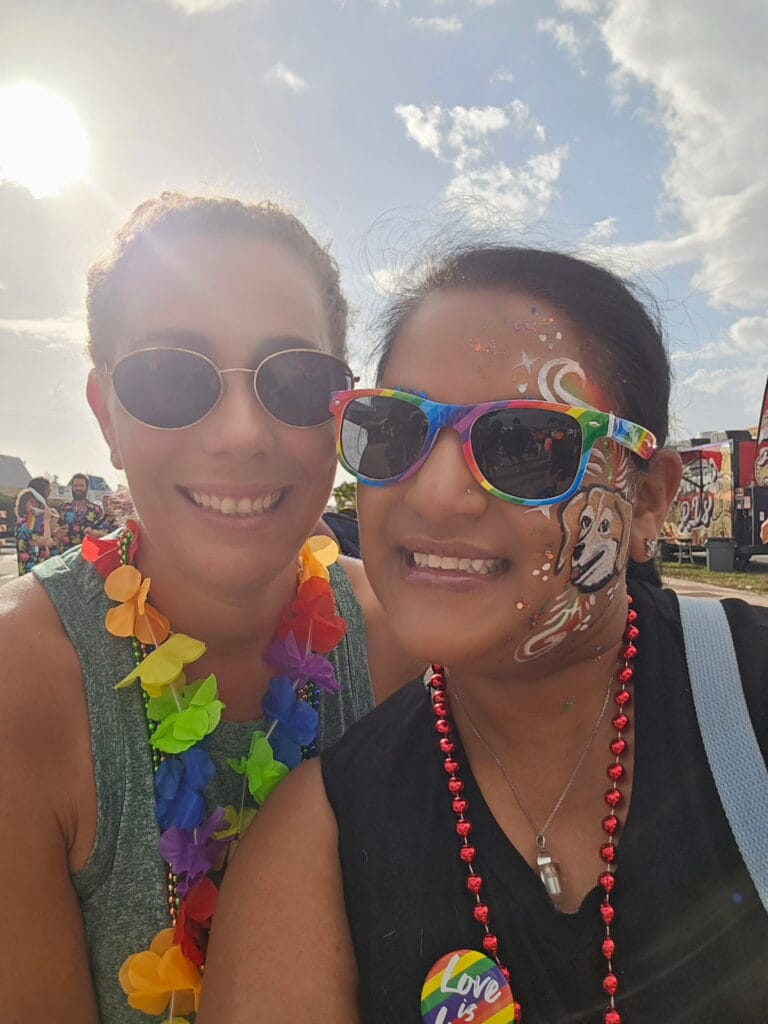 Attendees smiling at the Cape Coral pride festival wearing rainbow accessories and face paint.