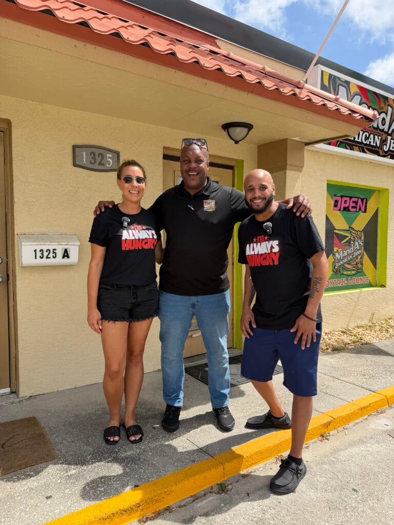 Clients standing outside Manda’s Jerk Chicken restaurant with owner in Cape Coral