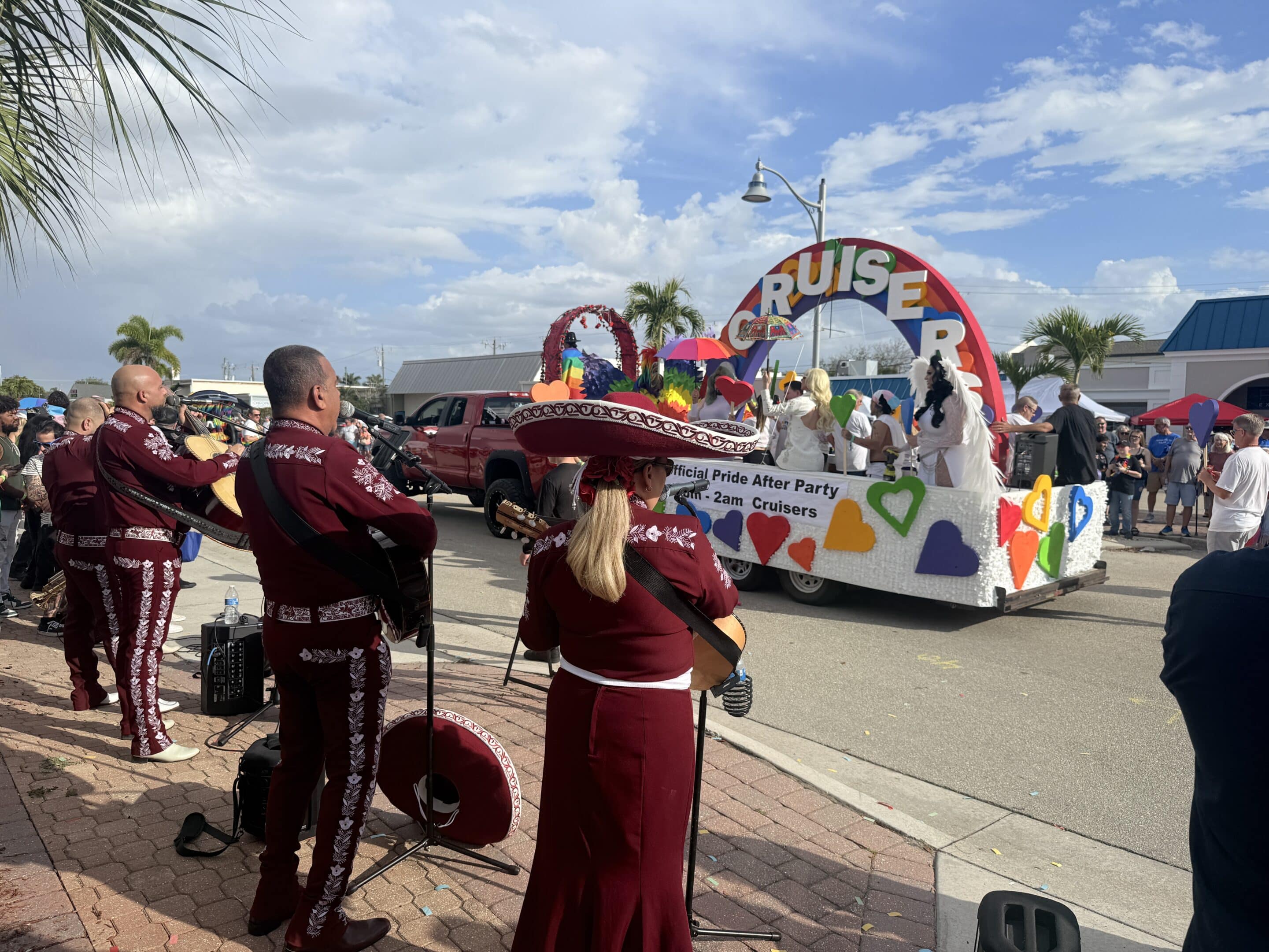 Pride festival parade float in downtown Cape Coral featuring colorful hearts and performers celebrating in the street.