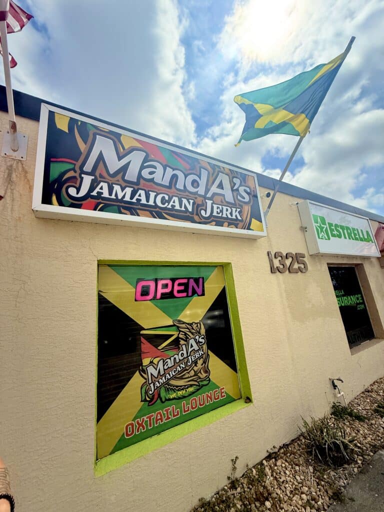 Exterior of Manda’s Jamaican Jerk in Cape Coral with open sign and Jamaican flag