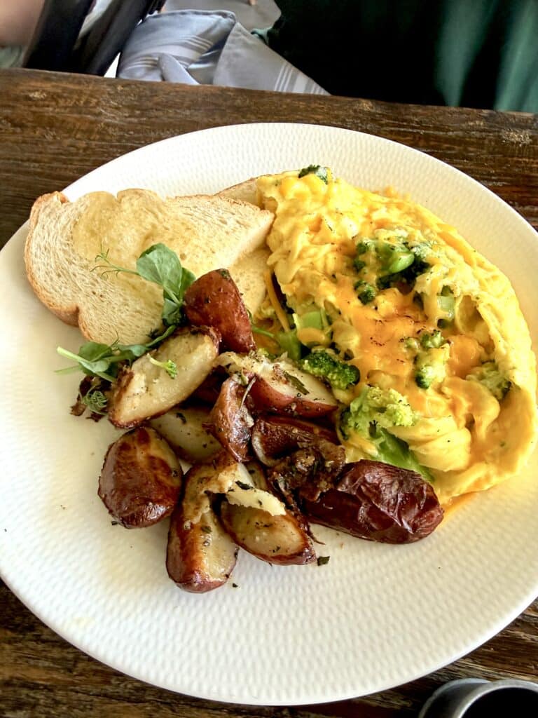 Farm-to-table brunch plate with eggs, potatoes, toast, fresh greens, and broccoli at Blossom & Brie.